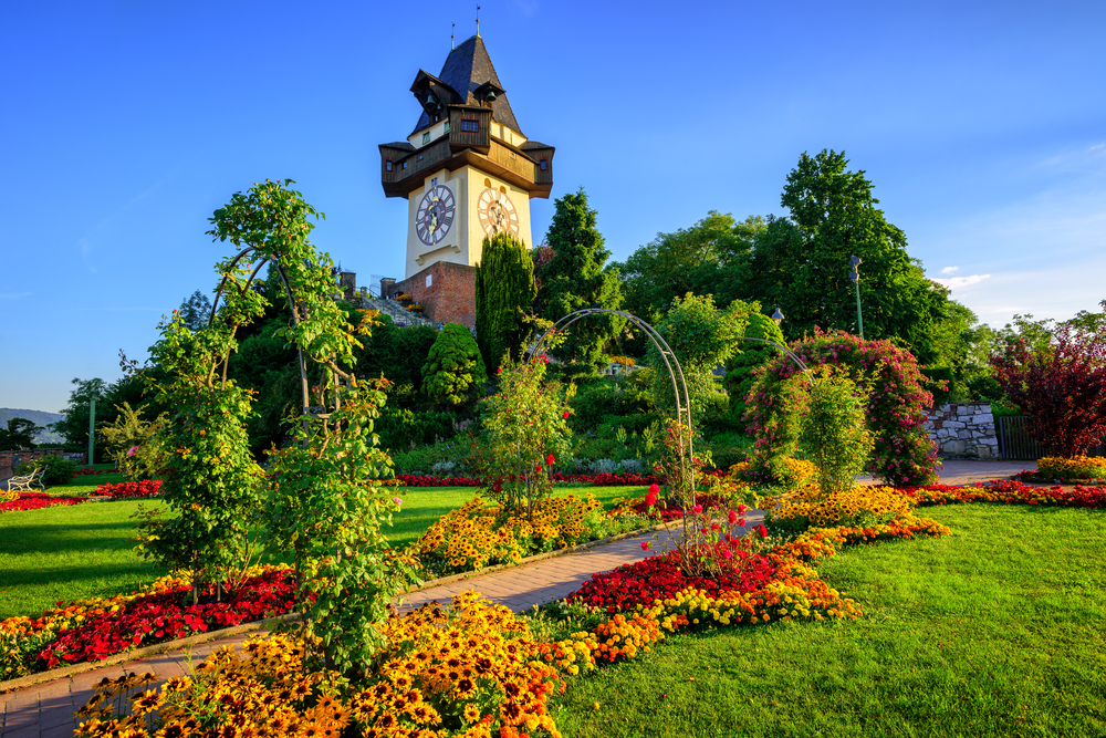 The medieval Clock tower Uhrturm in flower garden on Shlossberg hill, Graz, Austria
